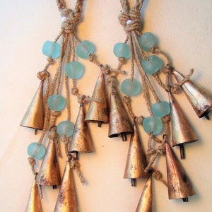 May include: Two sets of brown rope tassels with blue glass beads and copper bells hanging from them.