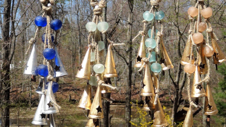 May include: A set of four wind chimes with different colored glass beads and metal bells. The chimes are made of natural twine and have a rustic look.