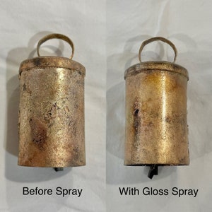 May include: Two antique-style bells, one with a matte finish and the other with a glossy finish. The bells are made of metal and have a gold color. The bell on the left is labeled "Before Spray" and the bell on the right is labeled "With Gloss Spray".