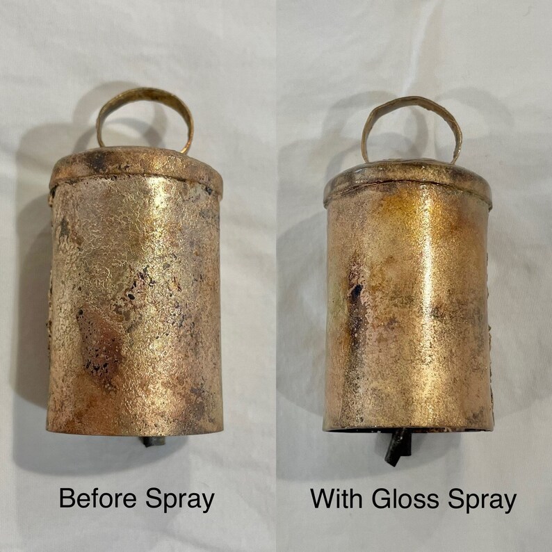 May include: Two antique-style bells, one with a matte finish and the other with a glossy finish. The bells are made of metal and have a gold color. The bell on the left is labeled "Before Spray" and the bell on the right is labeled "With Gloss Spray".
