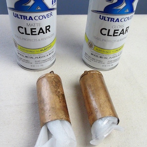 May include: Two cans of Rust-Oleum Painter's Touch 2X Ultra Cover clear spray paint. One can is matte finish and the other is gloss finish. Both cans are 12 oz. and are on a white surface.