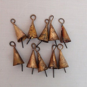 Op de afbeelding: Een verzameling van acht kleine, goudkleurige bellen met een lus aan de bovenkant. De bellen hangen aan een touwtje en zijn allemaal verschillend van grootte.