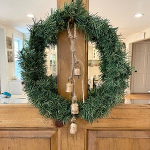 Peut inclure: Une couronne de No&euml;l artificielle verte avec une corde et cinq petites cloches dor&eacute;es qui pendent.