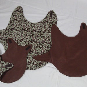 May include: Three brown fabric dog vests with velcro closures. One vest has a camouflage pattern.