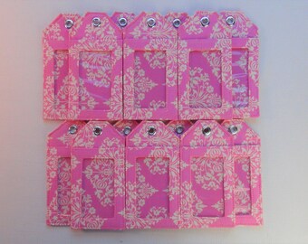 May include: A set of twelve pink fabric ID badge holders with a white floral pattern and clear plastic windows. Each holder has a silver eyelet.