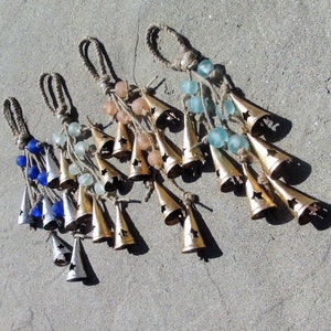May include: Four sets of wind chimes with different colored glass beads and gold bells. Each set has a different color of beads: blue, green, pink, and white.