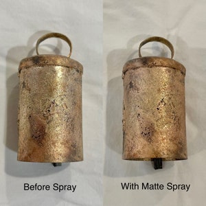 May include: Two antique-style metal bells, one with a shiny finish and the other with a matte finish. The bells are both the same size and shape, with a rounded top and a handle.