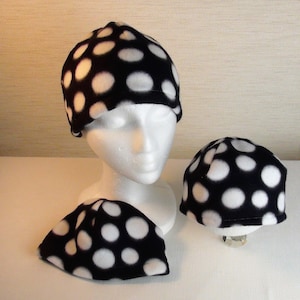 May include: Three black and white polka dot fleece hats. The hats are different sizes. The largest hat is on a white mannequin head.
