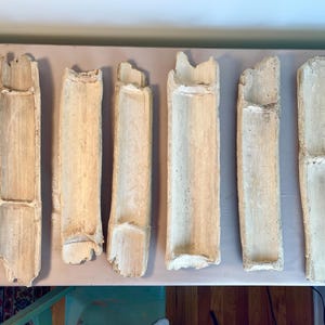 May include: Six natural bamboo trays, each with a rectangular shape and a smooth, light brown finish. The trays are arranged in a row on a light pink surface.