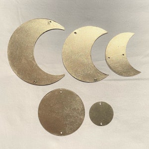 Può includere: Cinque forme in metallo color oro: una grande luna crescente, una luna crescente media, una piccola luna crescente, un cerchio grande e un cerchio piccolo.