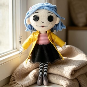 May include: A plush doll with button eyes, blue hair, and freckles, wearing a yellow coat, black skirt, and striped stockings. The doll is 11.02 inches (28 cm) tall.