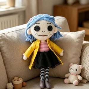 May include: A plush doll with blue hair, button eyes, and freckles, wearing a yellow raincoat, pink striped shirt, and black skirt. The doll has striped stockings and gray shoes. A small teddy bear and other decorative items are nearby.