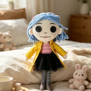 May include: A plush doll of a character with blue hair, button eyes, and freckles, wearing a yellow coat, black skirt, and striped stockings. The doll is approximately 12 inches tall and is sitting on a bed with a pink bunny and a teddy bear.