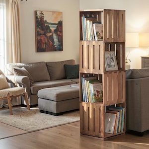 May include: A wooden crate bookshelf with four stacked sections. Each section holds books and a framed photograph. The bookshelf is made of light brown wood and stands in a living room setting.