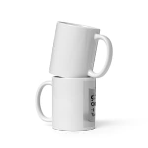 Può includere: Due tazze di ceramica bianca impilate l'una sull'altra. La tazza inferiore ha un'immagine rettangolare con testo. La tazza superiore è angolata. Entrambe le tazze hanno un manico curvo.