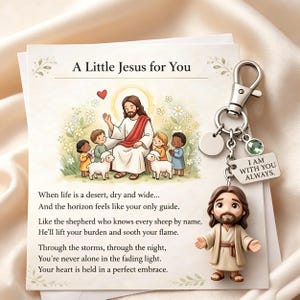 Może przedstawiać: Religijny brelok do kluczy z małą figurką Jezusa. Brelok zawiera kartę z ilustracją Jezusa z dziećmi i owcami oraz tekstem "A Little Jesus for You". Na etykiecie widnieje napis "I AM WITH YOU ALWAYS."