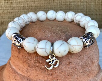 Buddha stretch bracelet in 10mm white turquoise with center ohm charm.