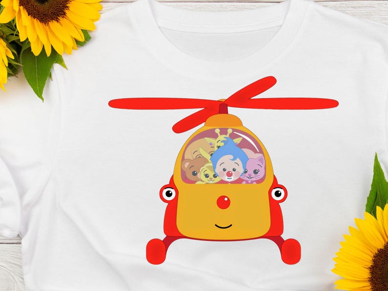 May include: White t-shirt featuring a cartoon helicopter design. The helicopter is yellow and red, with a smiling face and a propeller. Inside the helicopter are several cartoon characters with different colors and expressions.