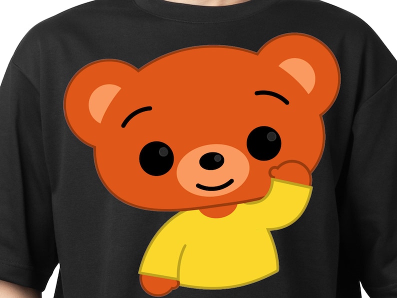May include: Black t-shirt featuring a cartoon bear with orange fur, black eyes, and a yellow shirt. The bear is waving with its right paw. The design is centered on the shirt.