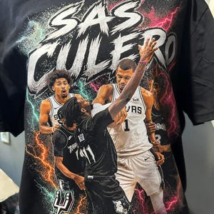 Puede incluir: Camiseta negra con un gráfico de equipo de baloncesto y el texto "SAS CULERO". El diseño incluye imágenes de jugadores de baloncesto y rayos en tonos rosa, azul y blanco. El logotipo del equipo es visible.