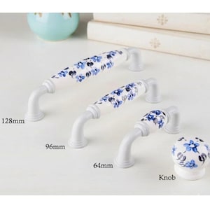 May include: White cabinet handles and a knob featuring blue floral patterns. The handles measure 12.8cm, 9.6cm, and 6.4cm in length. The knob has a complementary floral design. Ideal for cabinets, drawers, or furniture.