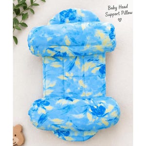 May include: A baby head support pillow featuring a blue and yellow floral pattern. The pillow has a rectangular center section with two rounded, padded bolsters at the top and bottom. The text Baby Head Support Pillow is printed in the corner.