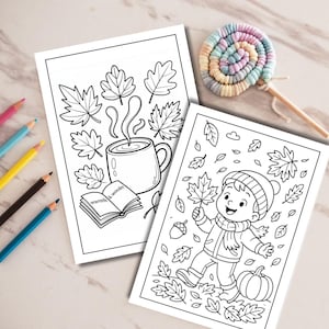 May include: Two black and white coloring pages featuring autumn themes. One page shows a steaming mug, leaves, and an open book with the text warmth & wonder. The other page depicts a child in a hat and scarf surrounded by falling leaves and a pumpkin.