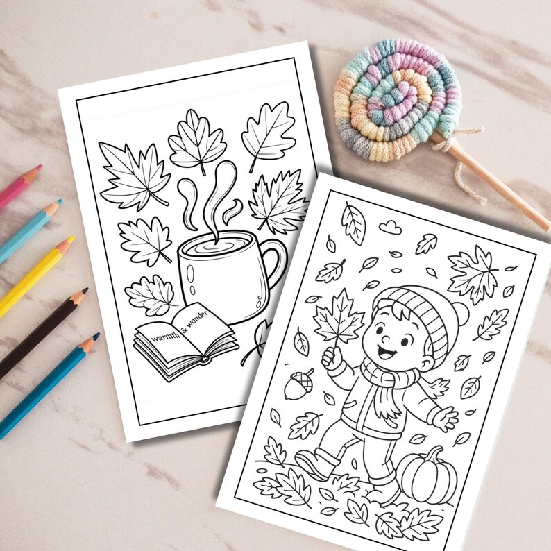 May include: Two black and white coloring pages featuring autumn themes. One page shows a steaming mug, leaves, and an open book with the text warmth & wonder. The other page depicts a child in a hat and scarf surrounded by falling leaves and a pumpkin.