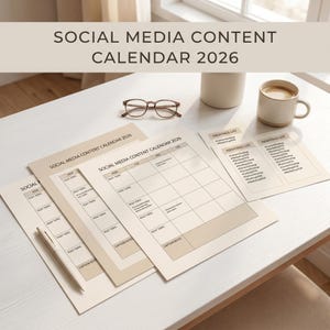Op de afbeelding: Een verzameling beige social media content kalenderbladen voor 2026, met een pen, een bril en een koffiemok op een witte tafel. De bladen hebben secties voor postonderwerpen en bijschriftnotities. De tekst "SOCIAL MEDIA CONTENT CALENDAR 2026" is zichtbaar.
