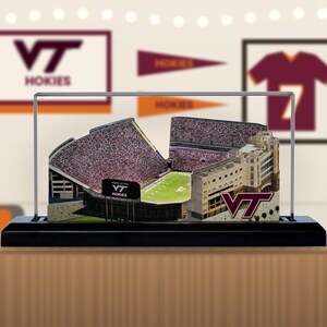 May include: A 3D model of a football stadium featuring a green field, packed stands, and a large building structure. The display includes the VT logo and the text HOKIES, all enclosed within a clear protective case on a black rectangular base.