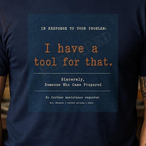 May include: A navy blue short-sleeve t-shirt featuring a dark blue square graphic with the text: IN RESPONSE TO YOUR PROBLEM: I have a tool for that. Sincerely, Someone Who Came Prepared. No further assistance required. Ref. Whenever I started carrying a knife.