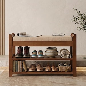 Peut inclure: Un banc &agrave; chaussures en bois avec une assise rembourr&eacute;e beige, dot&eacute; de deux &eacute;tag&egrave;res de rangement &agrave; lattes. Les &eacute;tag&egrave;res contiennent divers objets dont des bottes, des baskets, des bols en c&eacute;ramique, un textile roul&eacute;, des livres et des chaussures.