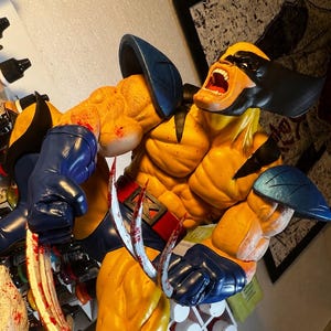 Peut inclure: Une figurine peinte à la main très détaillée du personnage Wolverine dans une pose dynamique et agressive. La figurine présente un costume jaune et bleu, un masque noir et des griffes métalliques étendues avec des éclaboussures de peinture rouge.