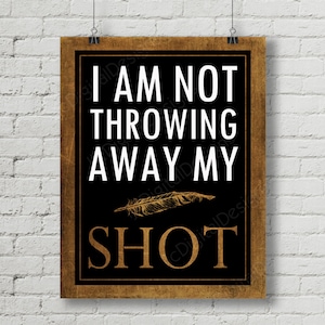 Op de afbeelding: Een zwart en gouden bord met de tekst "I AM NOT THROWING AWAY MY SHOT" met een gouden veren afbeelding.