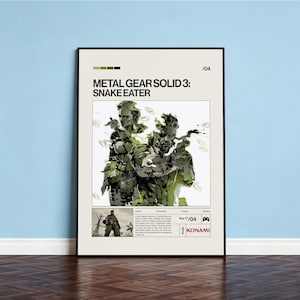 Puede incluir: Un póster enmarcado de Metal Gear Solid 3: Snake Eater. El póster presenta dos personajes en camuflaje, sosteniendo armas. El título está en texto negro en negrita, con el logotipo de Konami en la parte inferior.