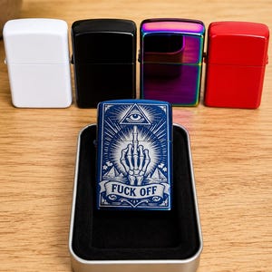 May include: A collection of lighters in various colors: white, black, iridescent, and red. A blue lighter in a metal case features a graphic design with an eye, hand, and the text "FUCK OFF". The lighters are displayed on a wooden surface.