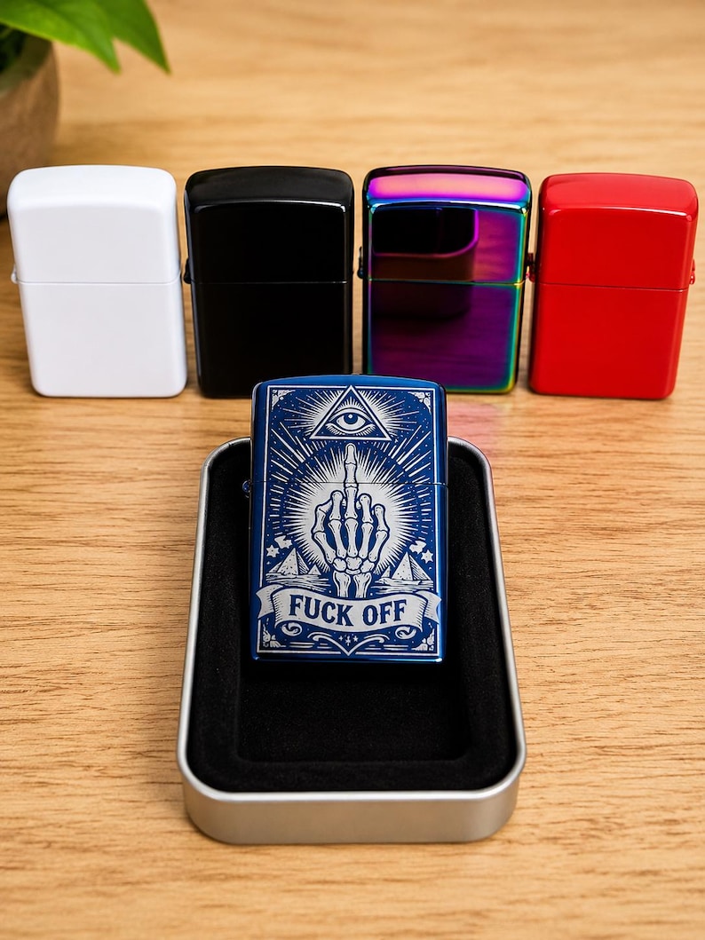 May include: A collection of lighters in various colors: white, black, iridescent, and red. A blue lighter in a metal case features a graphic design with an eye, hand, and the text "FUCK OFF". The lighters are displayed on a wooden surface.