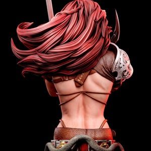 May include: A detailed bust sculpture of a warrior figure with long, flowing red hair, seen from the back. The figure wears brown leather straps, a silver shoulder pauldron with ornate engravings, and stands on a base featuring a coiled snake.