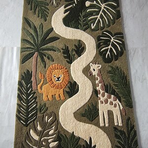 "Jungle safari themed tufted area rug featuring a lion, giraffe, tropical palm leaves, and a winding cream pathway. The rug is displayed in a children's playroom with wooden furniture, plants, and soft natural lighting, creating a cozy nursery and playroom decor setting."