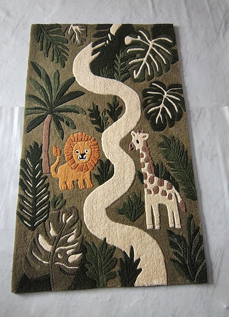 May include: A rectangular tufted rug featuring a jungle scene with a winding cream-colored path. The design includes a yellow lion with an orange mane, a cream and brown giraffe, and various green palm leaves and trees on an olive green background.