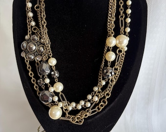 Collar vintage de Lia Sophia con capas de hematita y perlas de imitación, con cadenas de oro envejecido.