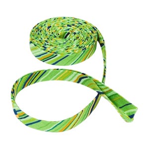 May include: A roll of fabric bias tape featuring a diagonal striped pattern in shades of lime green, yellow, and dark navy blue. The tape is coiled into a circular spool with one end extending outward, displaying the continuous multi-colored design.