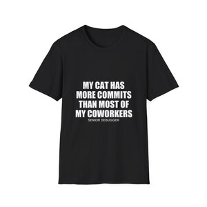 May include: Black t-shirt with white text that reads "MY CAT HAS MORE COMMITS THAN MOST OF MY COWORKERS" and "SENIOR DEBUGGER" below. The shirt is a short-sleeved crew neck.