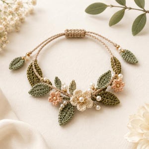 Può includere: Un braccialetto all'uncinetto fatto a mano con un design floreale. Il braccialetto ha un cordoncino beige con foglie verde oliva, fiori color pesca e crema e piccoli accenti di perle. La chiusura regolabile è un cordoncino beige intrecciato.
