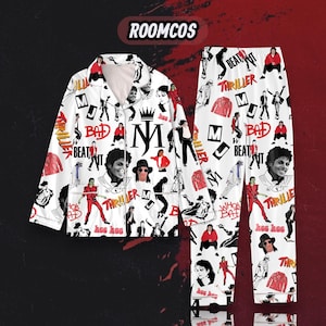 Può includere: Un set di pigiama bianco composto da una camicia a maniche lunghe con bottoni e pantaloni abbinati. Il tessuto presenta una stampa grafica ripetuta di Michael Jackson in varie pose, insieme alle scritte "Thriller", "Bad", "Beat It", "MJ" e "Hee Hee".