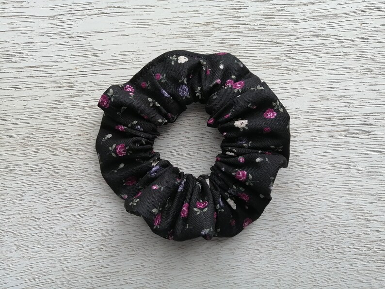 May include: Black scrunchie with a small white and purple floral print.