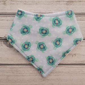 May include: A light blue bandana with a pattern of green sea turtles with flowers and starfish on a white background.