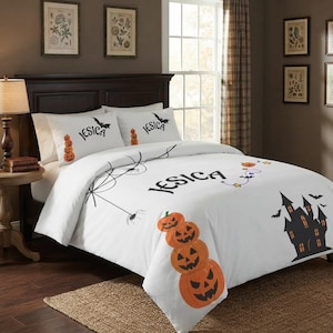 Può includere: Un set di biancheria da letto bianco con il nome JESICA in caratteri neri. Il design include una pila di zucche di Halloween arancioni, la sagoma nera di una casa stregata, una ragnatela, pipistrelli e luci decorative sul copripiumino.