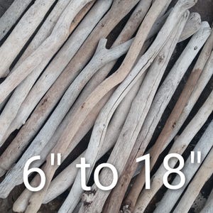 May include: A collection of weathered driftwood pieces, ranging from 6 to 18 inches in length. The wood displays a variety of natural colors, including light gray, beige, and brown. The pieces are arranged in a diagonal pattern.