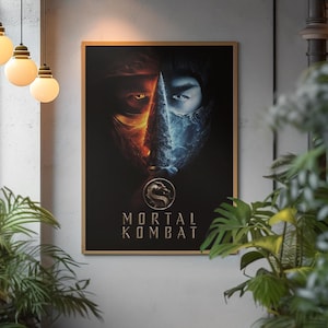 Może przedstawiać: Oprawiony plakat "Mortal Kombat" z podzielonym projektem twarzy z pomarańczowymi i lodowoniebieskimi elementami. Logo gry znajduje się na dole. Plakat jest oprawiony w drewnianą ramę i zawieszony na jasnoszarej ścianie.
